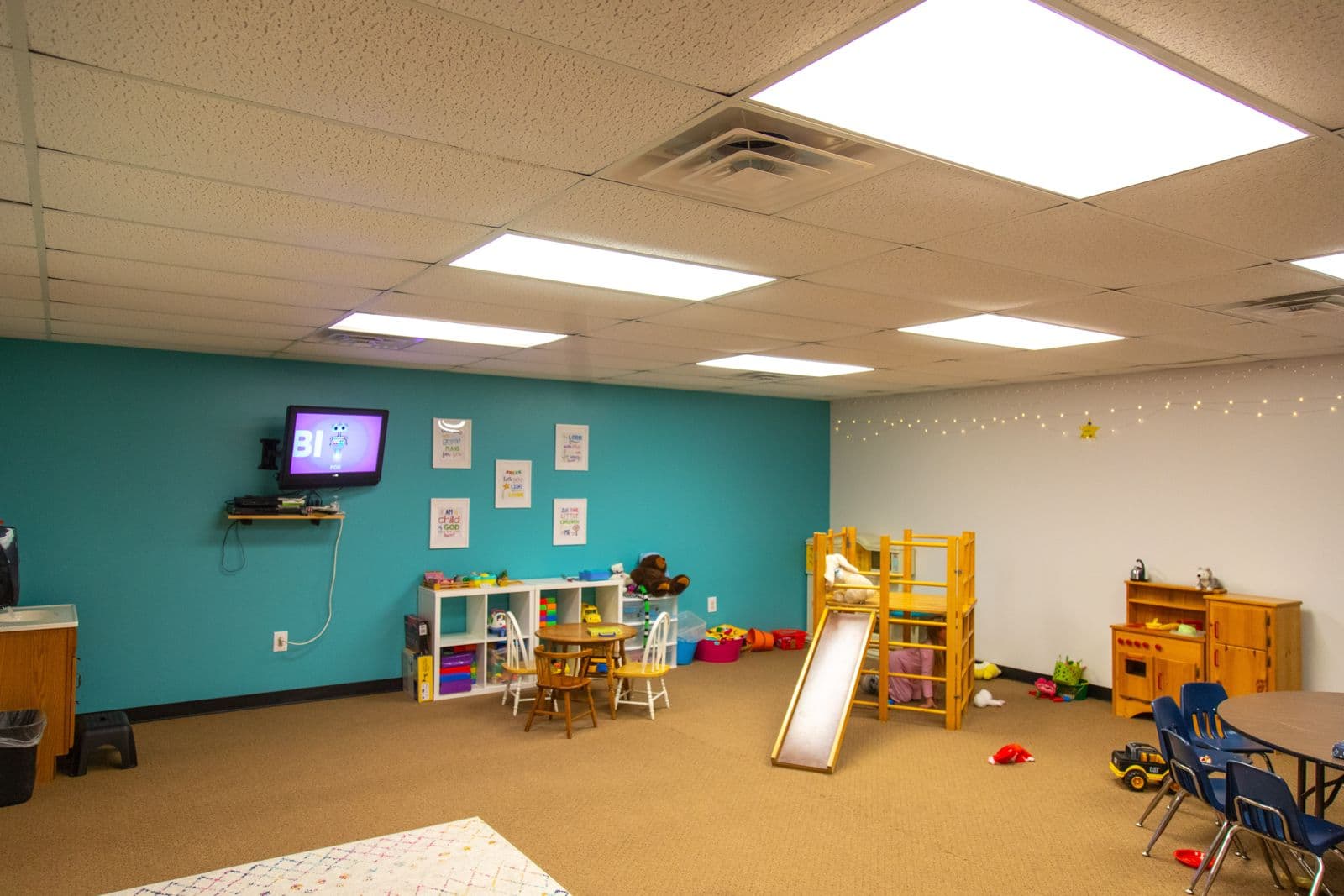 A bright classroom with a play loft, small tables, and toy shelves
